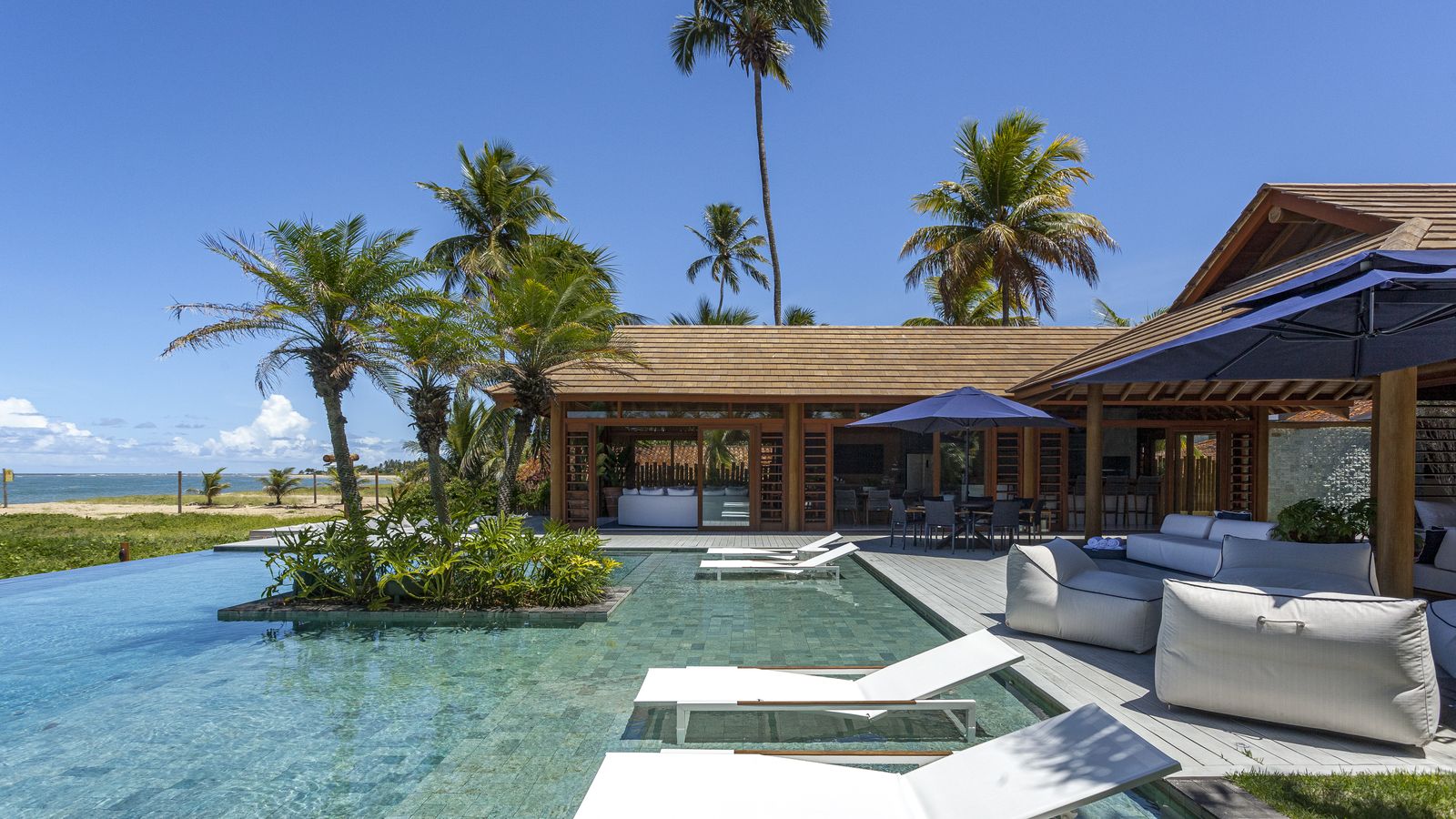 Piscina e área externa da Villa Capri de dia, com vista para o mar