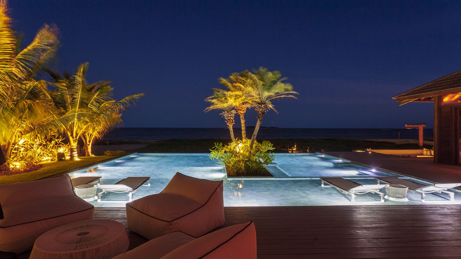 Piscina de borda infinita da Villa Capri à noite, de frente para o mar