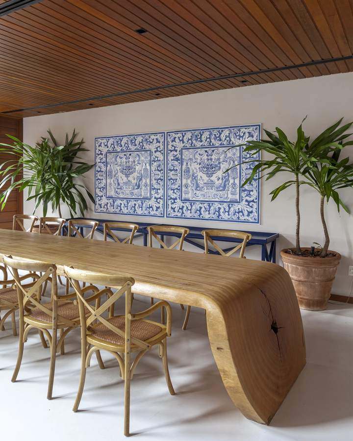 Mesa de jantar em tronco único sob painel de azulejos portugueses
