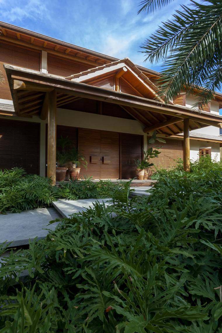 Chegada pela rua — muxarabis de madeira e jardim de philodendros