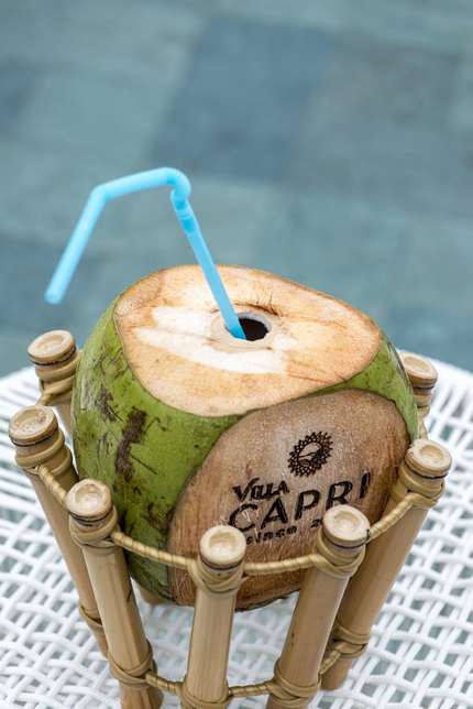 Água de coco com a marca Villa Capri gravada, à beira da piscina